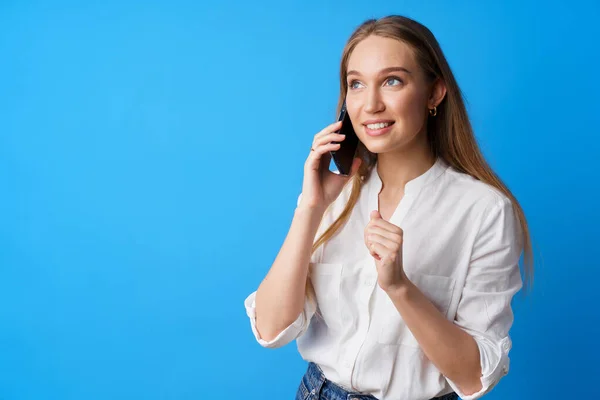 Feliz sorrindo jovem mulher falando ao telefone contra fundo azul — Fotografia de Stock
