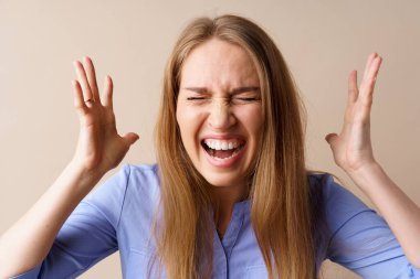 Kızgın stresli genç kadın bej arka planda