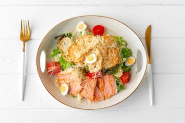 Beyaz ahşap arka planda ızgara tavuklu Sezar salatası