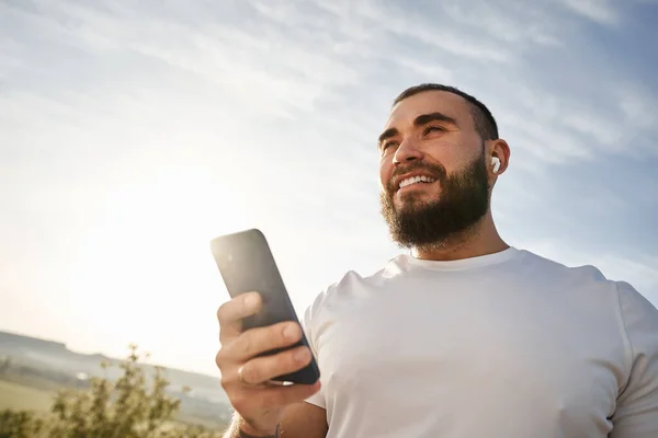 Fiatal férfi használja a mobiltelefon, miközben séta a vidéken — Stock Fotó