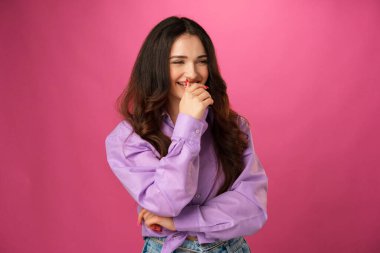 Genç mutlu kadın pembe arka planda gülümsüyor.