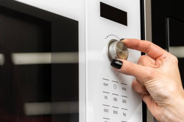 Kadın mikrodalga fırında düğmeye basıyor.