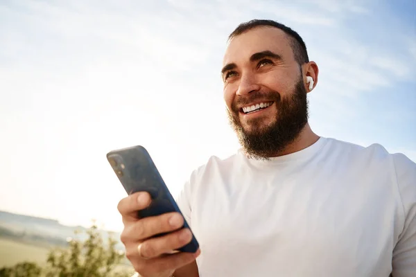 Fiatal férfi használja a mobiltelefon, miközben séta a vidéken — Stock Fotó