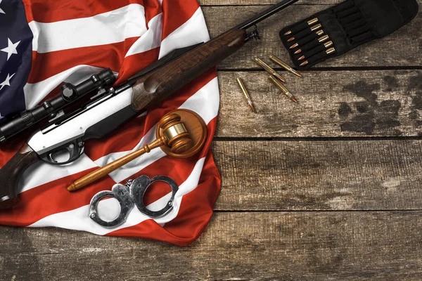 Wooden judge gavel and hunting rifle over USA flag on wooden background — Stock Photo, Image