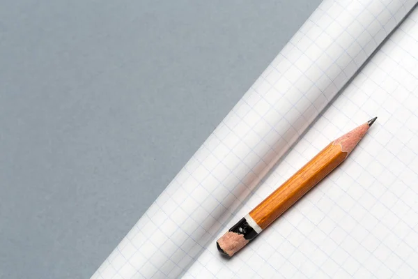 Rövid kopott ceruza jegyzettömbbel a szürke asztalon — Stock Fotó