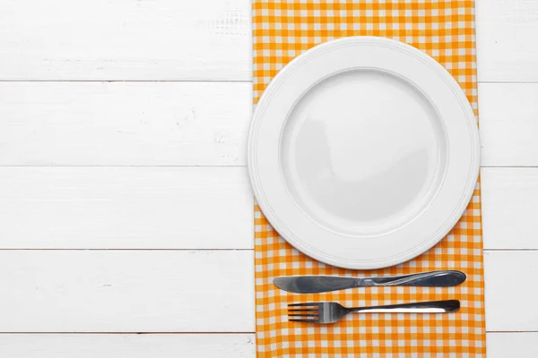 Пустая тарелка и полотенце на фоне деревянного стола. — стоковое фото