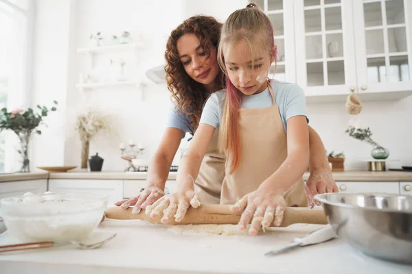 Menina adolescente ajudando sua mãe a cozinhar massa em sua cozinha em casa — Fotografia de Stock