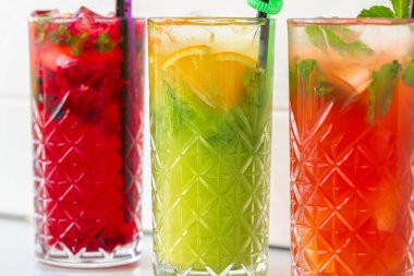 Beyaz ahşap arka planda üç farklı ferahlatıcı limonata.