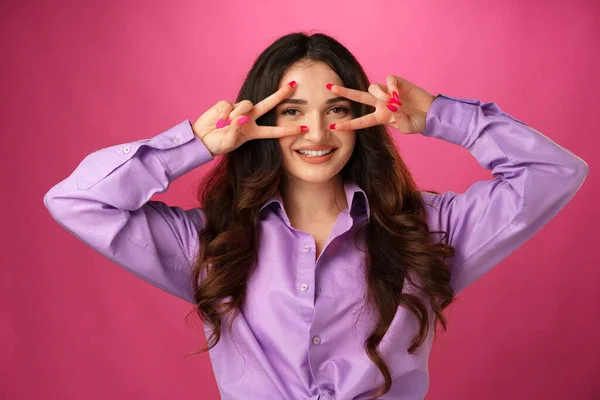 Mujer sonriente feliz mostrando signo de victoria sobre fondo rosa — Foto de Stock