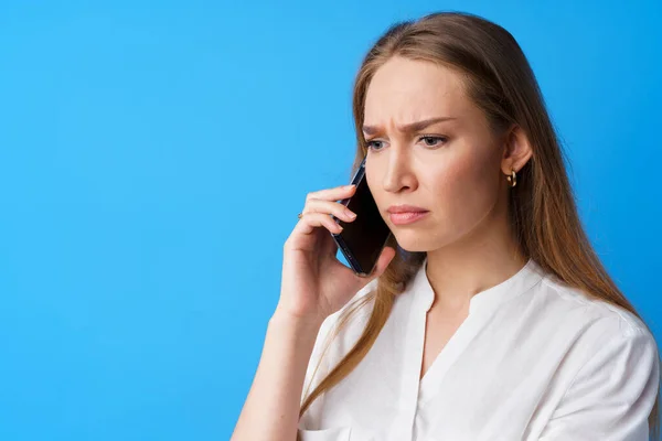 Boldogtalan nő beszél telefonon stresszes a rossz hír, kék háttér — Stock Fotó