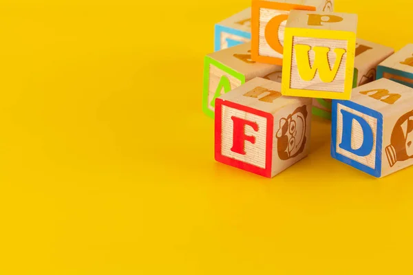 Kleurrijke houten blokken met letters op een gele achtergrond — Stockfoto