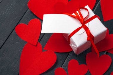 Tahta masada kırmızı kalpler olan hediye kutusu.