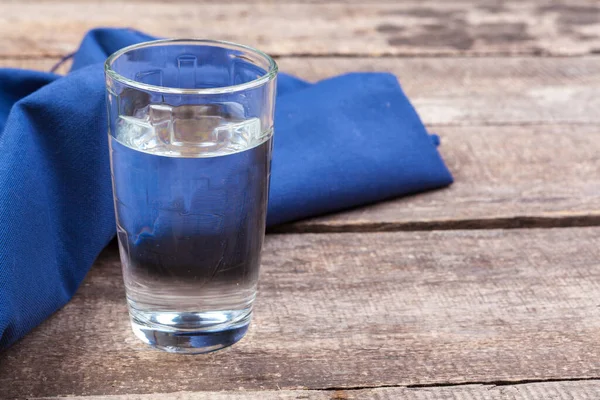 Un vaso de agua sobre una mesa de madera — Foto de Stock
