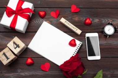 Sevgililer Günü geçmişi. Boş boş defter, hediye kutusu, beyaz arka planda çiçekler, üst manzara. Metin için boş alan