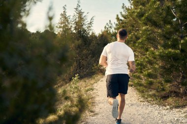 Genç kaslı erkek sporcu tepeye doğru koşuyor.