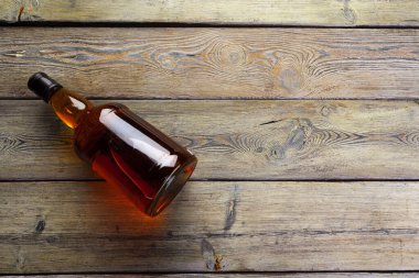 Viski şişesi koyu ahşap arka planda düz yatıyordu.