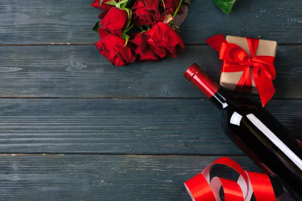 バレンタインデーのグリーティングカード。木製のテーブルの上に赤いバラの花、ワイン、ギフトボックス. — ストック写真