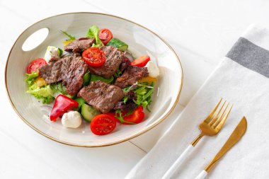 Ahşap masada sebze salatalı biftek fileto.