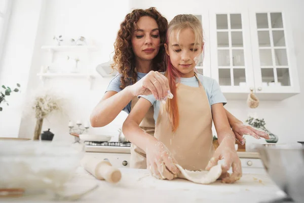 Menina adolescente ajudando sua mãe a cozinhar massa em sua cozinha em casa — Fotografia de Stock