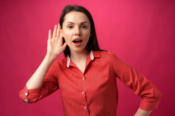 Reação de mulheres jovens no que ouviu, surpresa, no fundo rosa — Fotografia de Stock