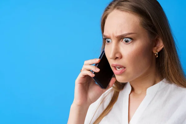 Mujer infeliz hablando por teléfono estresado con malas noticias, fondo azul — Foto de Stock