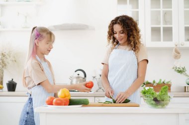 Anne ve kız mutfakta sebze salatası hazırlıyorlar.