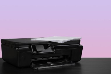 Masanın üzerinde mor arkaplana karşı ev lazer yazıcısı