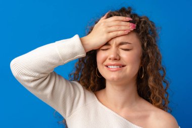 Endişeli, stresli, pişman genç bir kadın başını tutuyor.