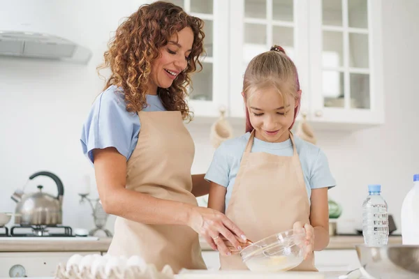 Moeder en tiener dochter maken deeg voor gebak samen in de keuken — Stockfoto