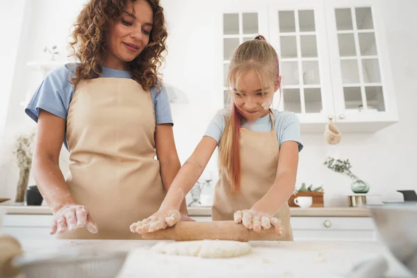 Menina adolescente ajudando sua mãe a cozinhar massa em sua cozinha em casa — Fotografia de Stock