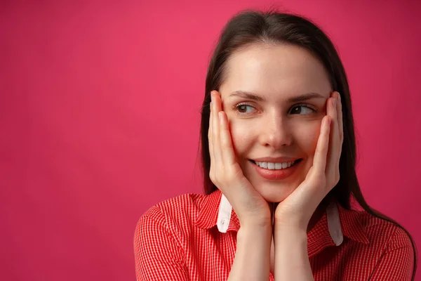 Close up of a young woman holding face in hands against pink background — Stock Photo, Image