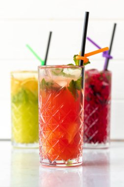 Beyaz ahşap arka planda üç farklı ferahlatıcı limonata.