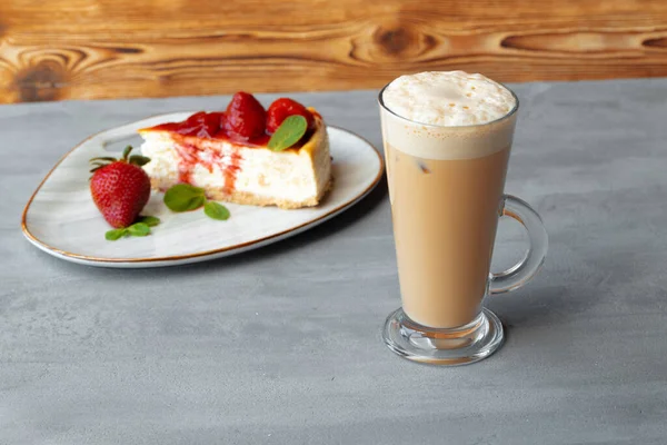 Glas latte kaffe och bit jordgubbscheesecake på grått bord — Stockfoto