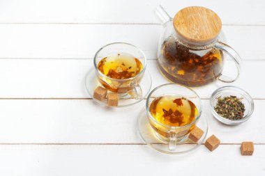 Çaydanlık ve fincanlar beyaz ahşap arka planda.