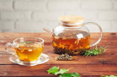 Ahşap masada bir fincan siyah çay ile camdan bir çaydanlık.