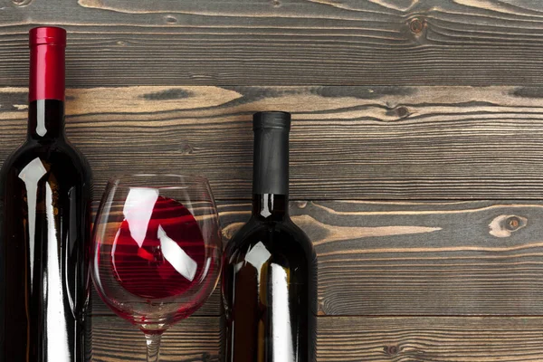 Glass and bottle with red wine on wooden background, top view — Stock Photo, Image