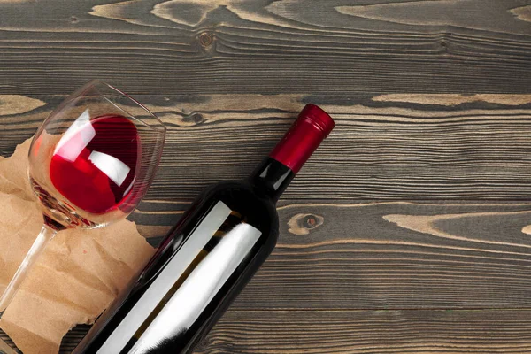 Glass and bottle with red wine on wooden background, top view — Stock Photo, Image