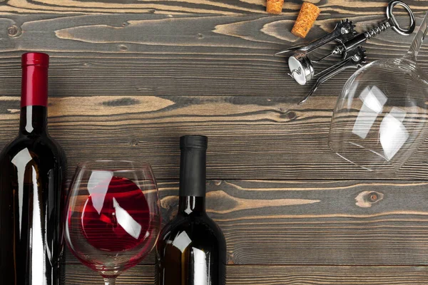 Бутылка вина, пробка и штопор на деревянном столе — стоковое фото