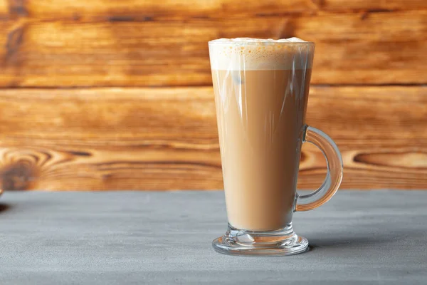 Glas av välsmakande aromatisk latte på trä bakgrund — Stockfoto