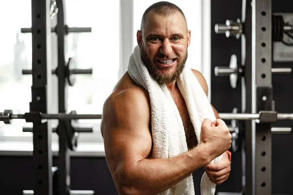 Cheerful smiling man bodybuilder standing in a gym