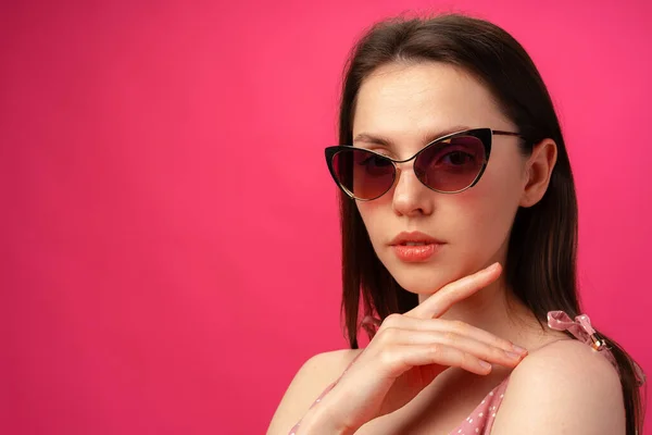 Jeune femme brune décontractée en lunettes de soleil sur fond rose — Photo