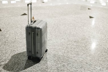Gri seyahat çantası boş havaalanı salonunda.