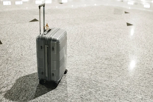 Valigia da viaggio grigia nella hall vuota dell'aeroporto — Foto Stock