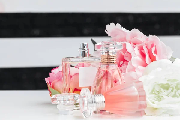 Botellas de perfume con flores sobre fondo claro —  Fotos de Stock