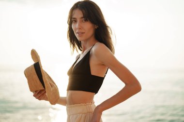 Sahilde gülümseyen genç kadın portresi.