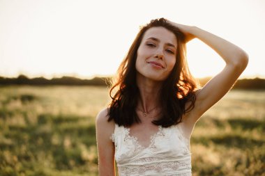 Gün doğumunda bir tarlada duran genç kadın manzaranın tadını çıkarıyor.