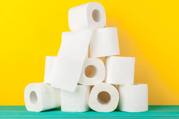 Rollos de papel higiénico apilados contra fondo de papel amarillo — Foto de Stock