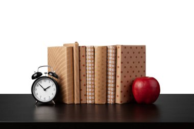Masaüstünde beyaz arkaplana karşı kitap ve elma yığını