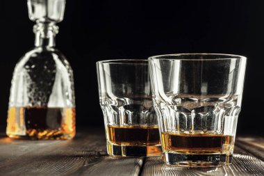 Eski ahşap masada viski bardağı ve şişe.