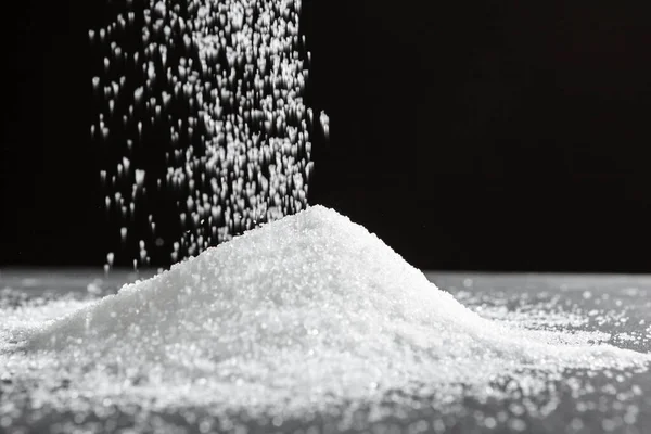 Verstreuter Zucker auf schwarzem Hintergrund in Nahaufnahme — Stockfoto